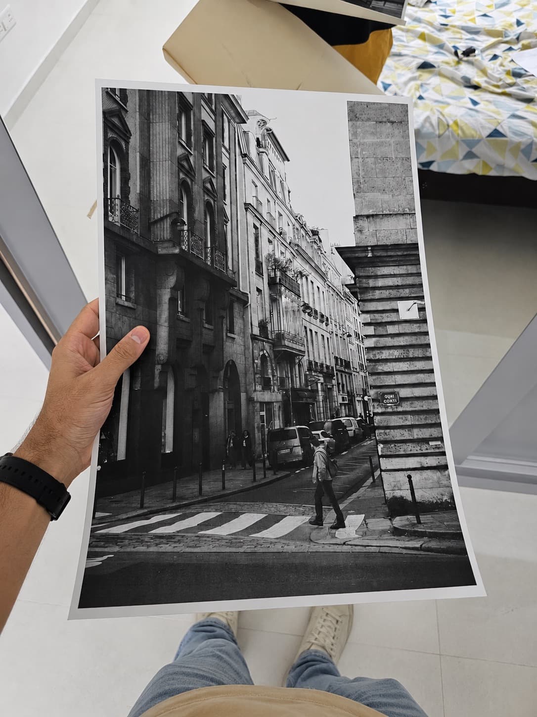Holding a freshly printed photograph of a Paris street corner
